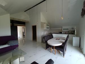 a living room with a table and chairs and a kitchen at Les terrasses de la loue au domaine de Tara in LʼHôpital-du-Grosbois