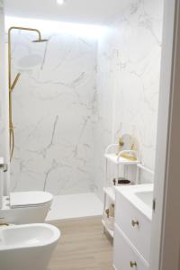 a white bathroom with a toilet and a sink at H2, vivienda turística in Jaén