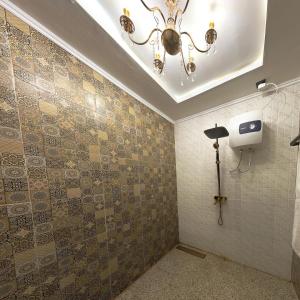 a bathroom with a chandelier and a tiled wall at Noerbaya House Bukittinggi in Bukittinggi +6 photos