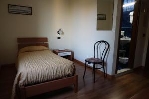 sypialnia z łóżkiem, krzesłem i lustrem w obiekcie Hotel Siros w Weronie