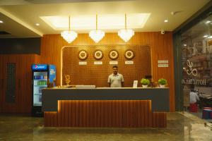 德瓦尔卡Hotel Leela's的一名男子站在餐厅柜台后面