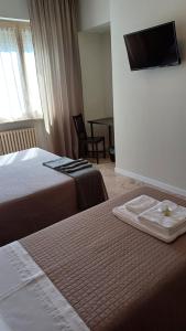 a hotel room with two beds and a tv on the wall at B&B Monté in Montesilvano