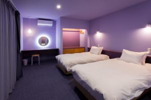 a hotel room with two beds and a purple wall at HOKKAIDO VILLA e2 in Nakafurano