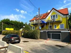 żółty dom z samochodem zaparkowanym na parkingu w obiekcie AJO Apartments - Alte Donau Terrace Studio - Self-Check-in w Wiedniu