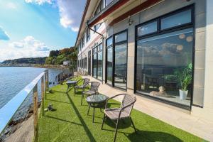 Una fila de sillas y mesas en un patio junto al agua. en La-se-ri Resort & Stay - Vacation STAY 63346v, en Himi