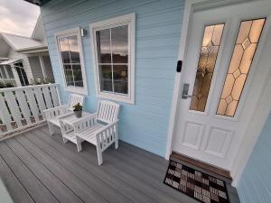 a porch with two white benches and a door at Light Blue in Tullimbar