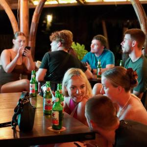 a group of people sitting at a table with beer bottles at The Social - Begadang Gili Air in Gili Islands
