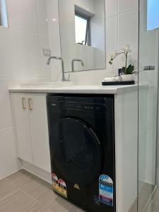 a black dishwasher under a sink in a bathroom at Redvue Holiday Apartments in Redcliffe