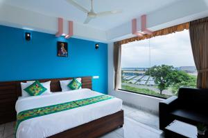 een slaapkamer met een blauwe muur, een bed en een raam bij Treebo Airsuite Airport Hotel in Cochin