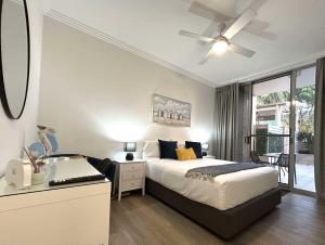 a bedroom with a bed and a desk and a window at Redvue Holiday Apartments in Redcliffe