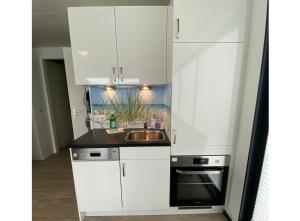 a kitchen with white cabinets and a sink at Ostsee Hausboot Boltenhagen - WELL Hausboote LP4 in Boltenhagen