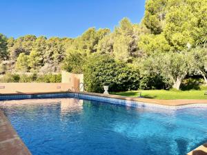 a swimming pool with blue water and trees in the background at Casa rural exclusiva con vista al mar en Calpe in Empedrola