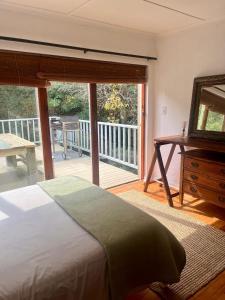 a bedroom with a bed and a balcony with a mirror at Paradise View Apartment in Knysna +11 photos