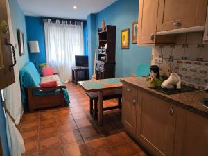 a kitchen with blue walls and a table and a couch at Apartamentos Andrea in Belmonte de Miranda