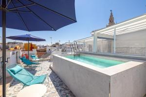 a swimming pool with two chairs and an umbrella at Hernando Colón Olehousing in Seville
