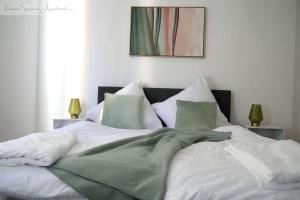 a large bed with white sheets and green pillows at Ludwigshafen-Bahnhofsresidenz in Ludwigshafen am Rhein