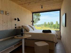 a bedroom with a bed and a couch and a window at Vineyard Cabins at Château Puynard in Berson