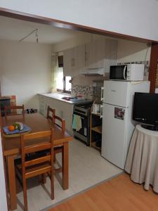 a kitchen with a table and a white refrigerator at Casa da fonte in Lavacolhos