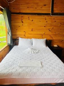 a bedroom with a white bed with a wooden wall at Khu Nghỉ dưỡng Sinh thái Nhà Lụa Retreat in Ấp Quảng Giáo