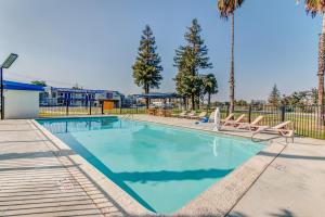 a swimming pool with lounge chairs and palm trees at Motel 6-Visalia, CA in Visalia