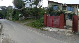 une maison avec un portail rouge au bord d'une route dans l'établissement Madhur Cottage Homestay, à Mukteswar