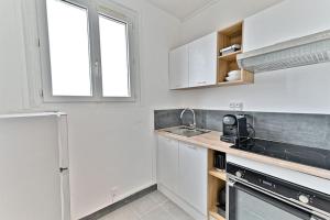 eine Küche mit weißen Schränken und einer Spüle und einem Fenster in der Unterkunft Studio lumineux et moderne à Montreuil - II in Montreuil