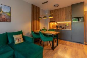 Una sala de estar con un sofá verde y una mesa. en Apartament Izerka z basenem i sauną - Stone Hill, en Szklarska Poręba