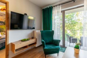 sala de estar con silla verde y TV en Apartament Izerka z basenem i sauną - Stone Hill, en Szklarska Poręba