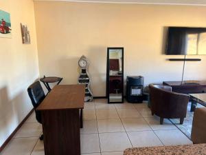 a living room with a table and a clock on the wall at Elegant Estates in Roodepoort