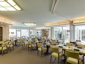 a dining room with tables and chairs and windows at Art Hotel Superior in Aachen