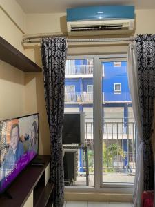 a living room with a window with a tv and a window at Apartemen Center Point Bekasi in Kayuringin