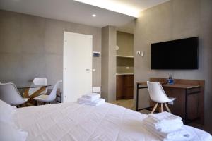 a bedroom with a white bed with a television on the wall at La Maison Latina Guest House in Latina