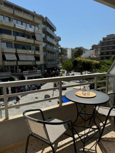 a table and chairs on a balcony with a beach at Siesta Luxury Apartment in Heraklio