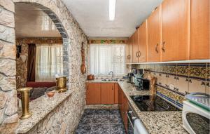 a kitchen with wooden cabinets and a stone wall at 2 Bedroom Cozy Apartment In Vidreres in Vidreres