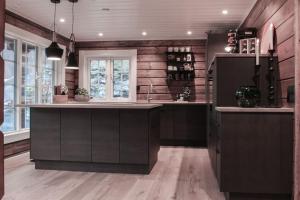 a kitchen with wooden walls and a large kitchen island at Tømmerhus i Geiranger Sentrum med panorama utsikt in Geiranger