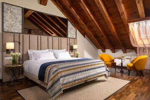 a bedroom with a large bed and two yellow chairs at NH Collection Madrid Palacio de Tepa in Madrid
