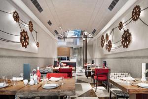 a restaurant with wooden tables and red chairs at NH Collection Madrid Palacio de Tepa in Madrid