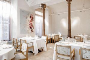 a dining room with white tables and chairs at NH Collection Madrid Palacio de Tepa in Madrid