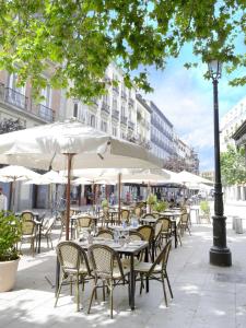 an outdoor cafe with tables and chairs and umbrellas at NH Collection Madrid Palacio de Tepa in Madrid