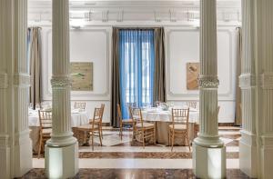 a dining room with tables and chairs and columns at NH Collection Madrid Palacio de Tepa in Madrid