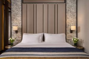 a bedroom with a bed with two lamps and flowers at NH Collection Madrid Palacio de Tepa in Madrid