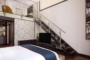 a bedroom with a staircase with a bed and a television at NH Collection Madrid Palacio de Tepa in Madrid