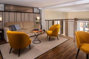 a living room with yellow chairs and a couch at NH Collection Madrid Palacio de Tepa in Madrid