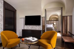 a hotel room with two chairs and a table and a bed at NH Collection Madrid Palacio de Tepa in Madrid