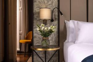 a vase of flowers on a table next to a bed at NH Collection Madrid Palacio de Tepa in Madrid