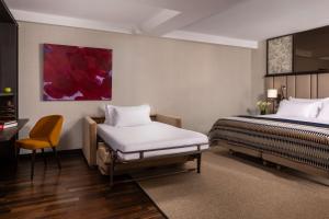 a hotel room with two beds and a chair at NH Collection Madrid Palacio de Tepa in Madrid