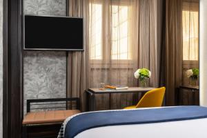 a bedroom with a bed and a tv on a wall at NH Collection Madrid Palacio de Tepa in Madrid