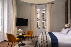 a hotel room with a bed and a table and chairs at NH Collection Madrid Palacio de Tepa in Madrid