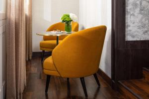 a table with two yellow chairs and a vase of flowers at NH Collection Madrid Palacio de Tepa in Madrid