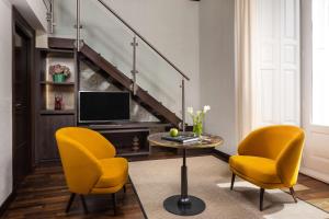 a living room with two chairs and a table and a tv at NH Collection Madrid Palacio de Tepa in Madrid